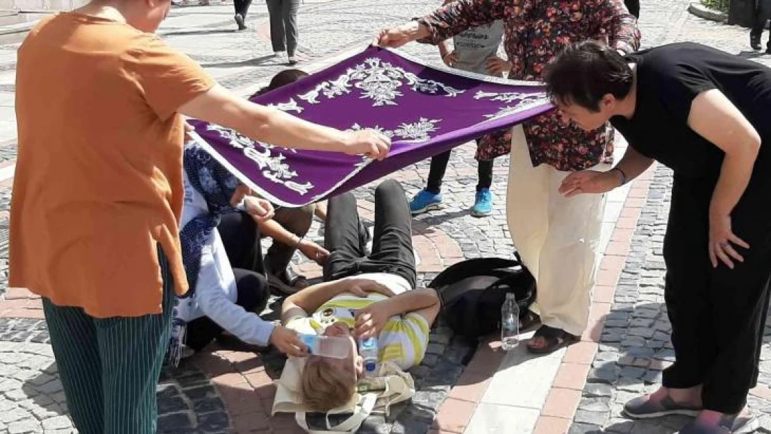 Kadınlar yerde yatan yaralıyı örtü ile güneşten korudu